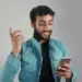 A happy young man smiling while looking at his phone, symbolizing the importance of reconnecting with family and support networks during and after recovery.